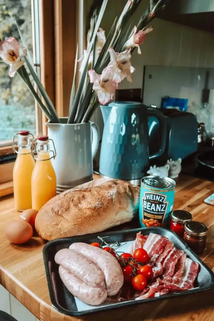 Breakfast ingredients in a Shepherd’s Hut kitchen, including sausages, bacon, tomatoes, bread and juice
